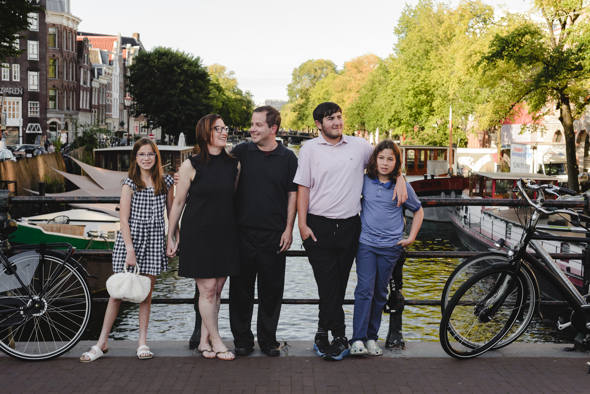 Family photo session in Amsterdam with canal behind, parents and children standing together