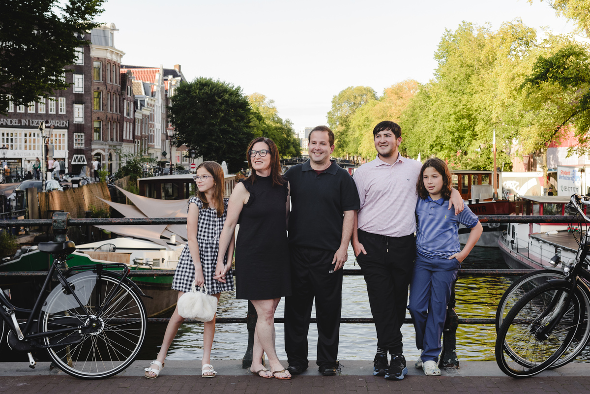 Family photo session in Amsterdam with canal behind, parents and children standing together