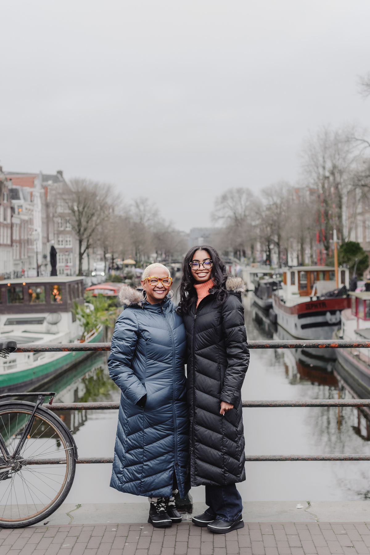 Mother and daughter walking hand in hand along Amsterdam canals during a holiday photo shoot