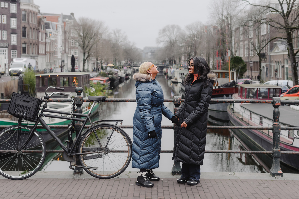 Mother and daughter walking hand in hand along Amsterdam canals during a holiday photo shoot