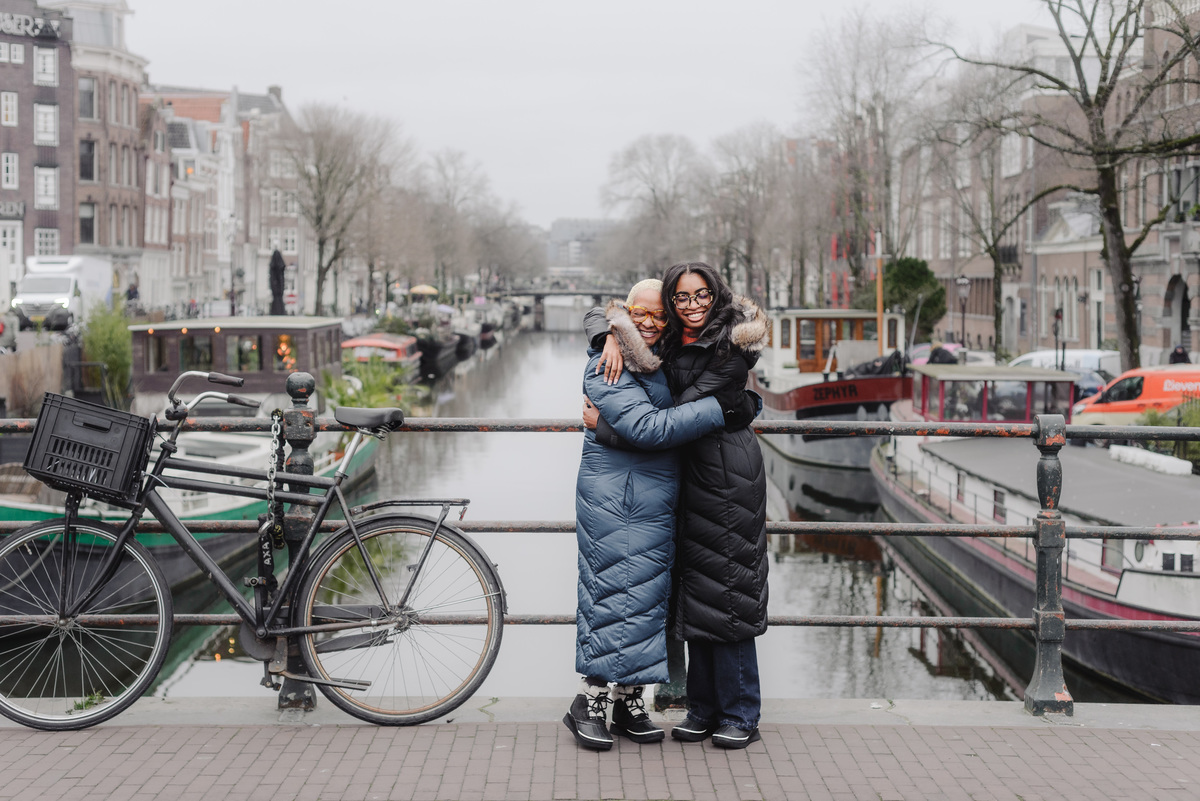 Mother and daughter walking hand in hand along Amsterdam canals during a holiday photo shoot