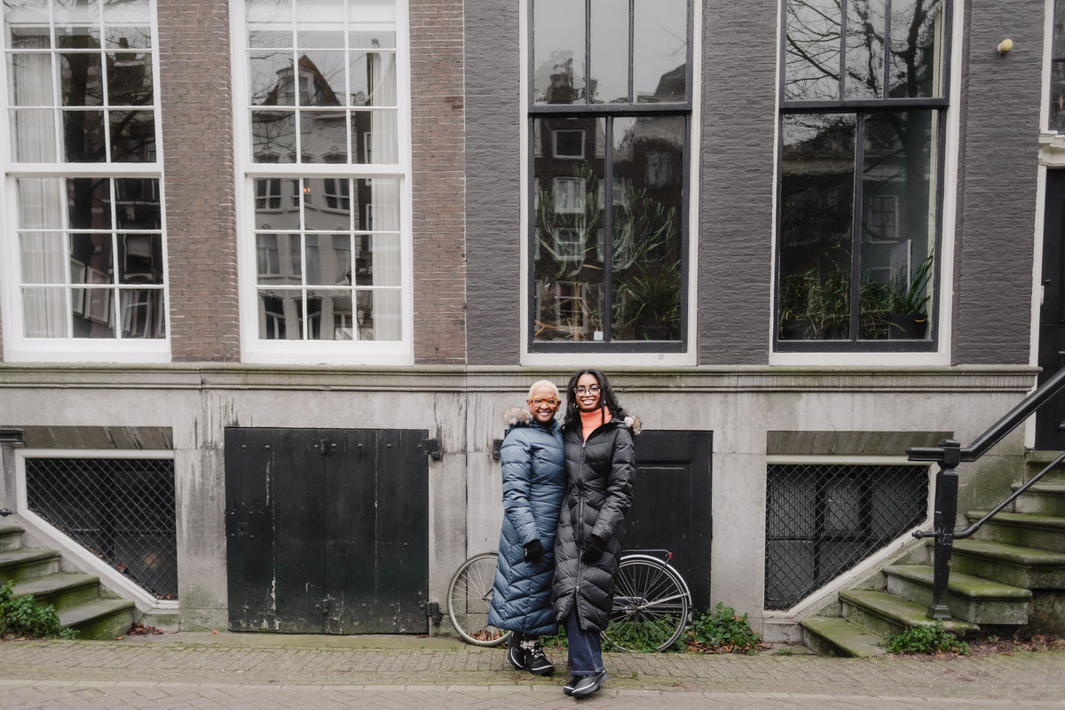 Mother and daughter standing side by side near an Amsterdam canal in soft winter light