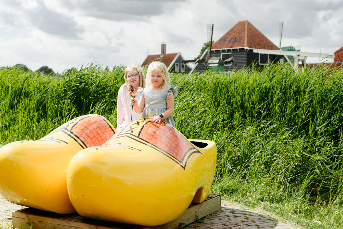 Kids portrait on giant traditional dutch wooden shows at Zaanse Schans village with houses in the background