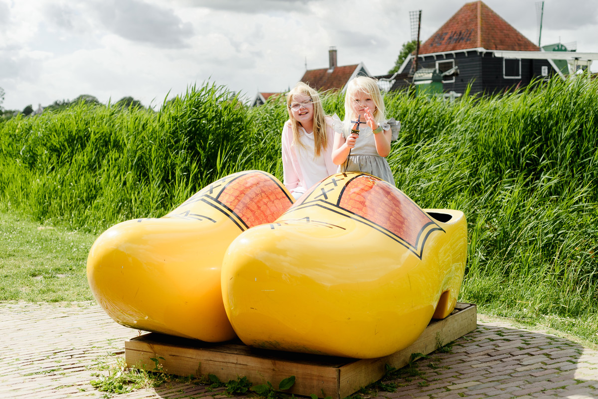 Kids portrait on giant traditional dutch wooden shows at Zaanse Schans village with houses in the background