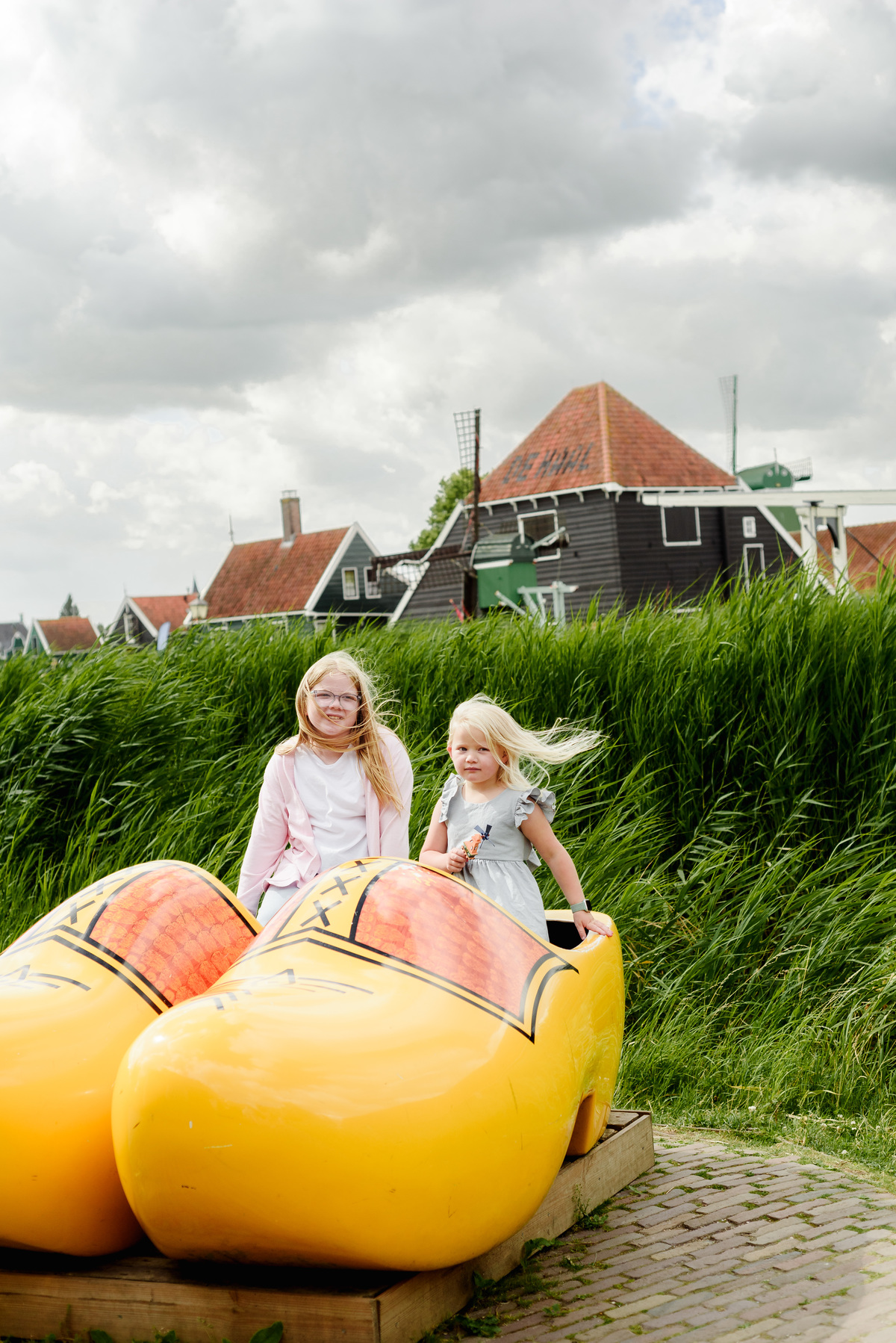 Kids portrait on giant traditional dutch wooden shows at Zaanse Schans village with houses in the background