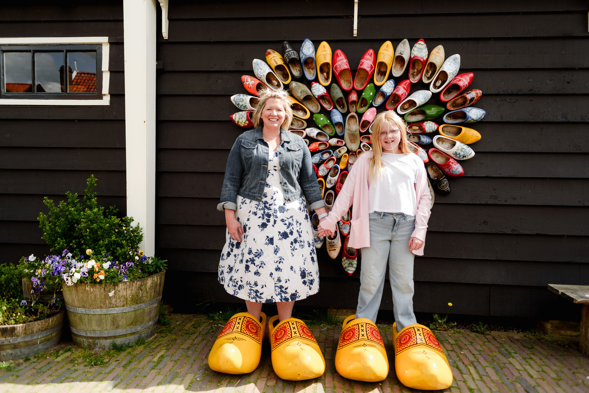 Mother and daughter portrait with large traditional Dutch wooden shoes and heart-shaped clogs displayed on the wall
