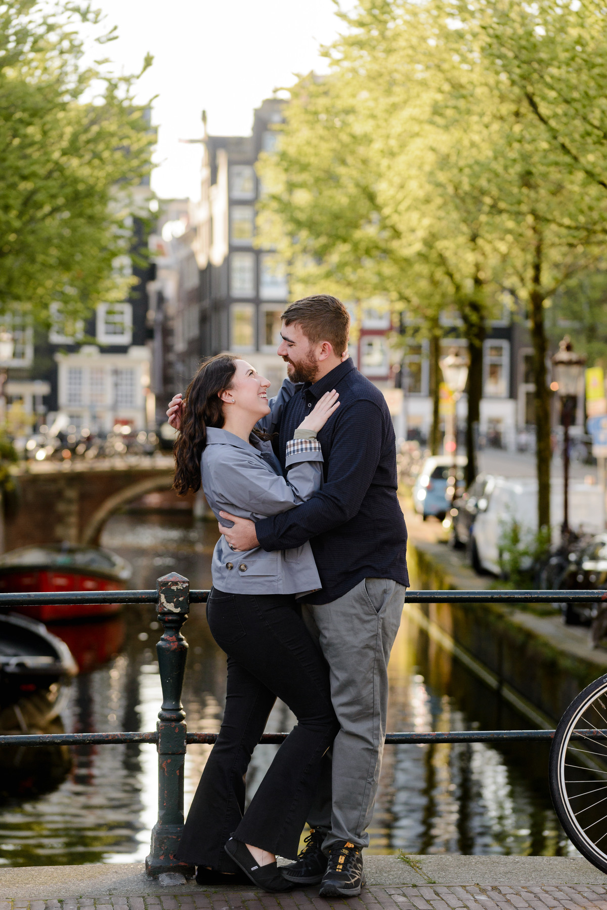 Couple hugging with the background of the historical houses, canals, and boats of the canal belt in Amsterdam during a photo session, a couple photo session in the canal belt 