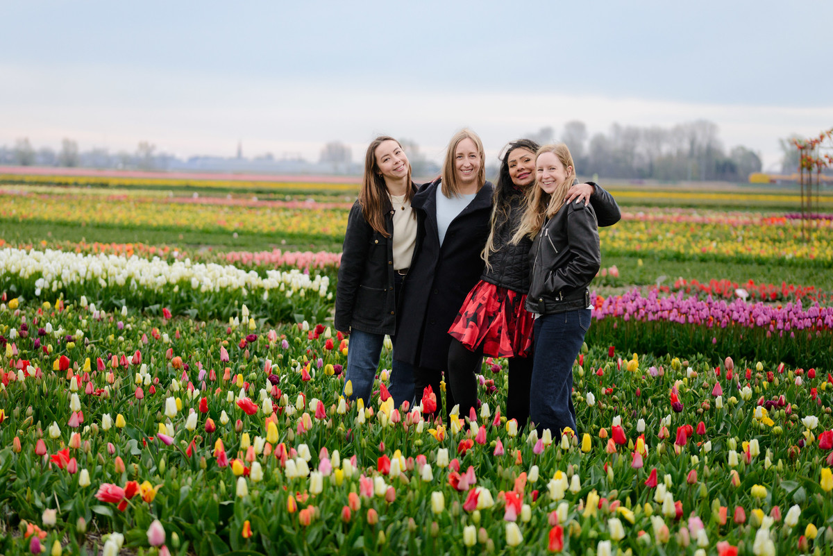 Four friends traveling in the Netherlands, posing in a field of tulips. This is a tulip experience in Amsterdam during Tulip Season 2026, during a photo session. 