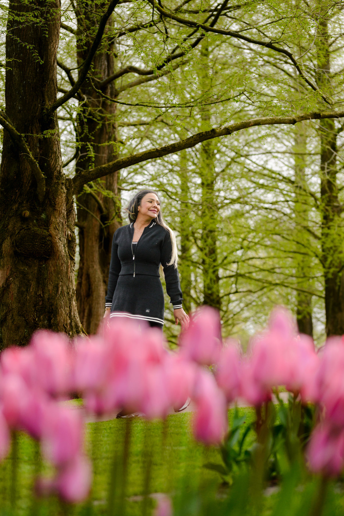 Solo traveller walking on a tulip garden. This is Keukenhof Gardens with lush trees in the background. Photo session taken in the tulip season 2026. 