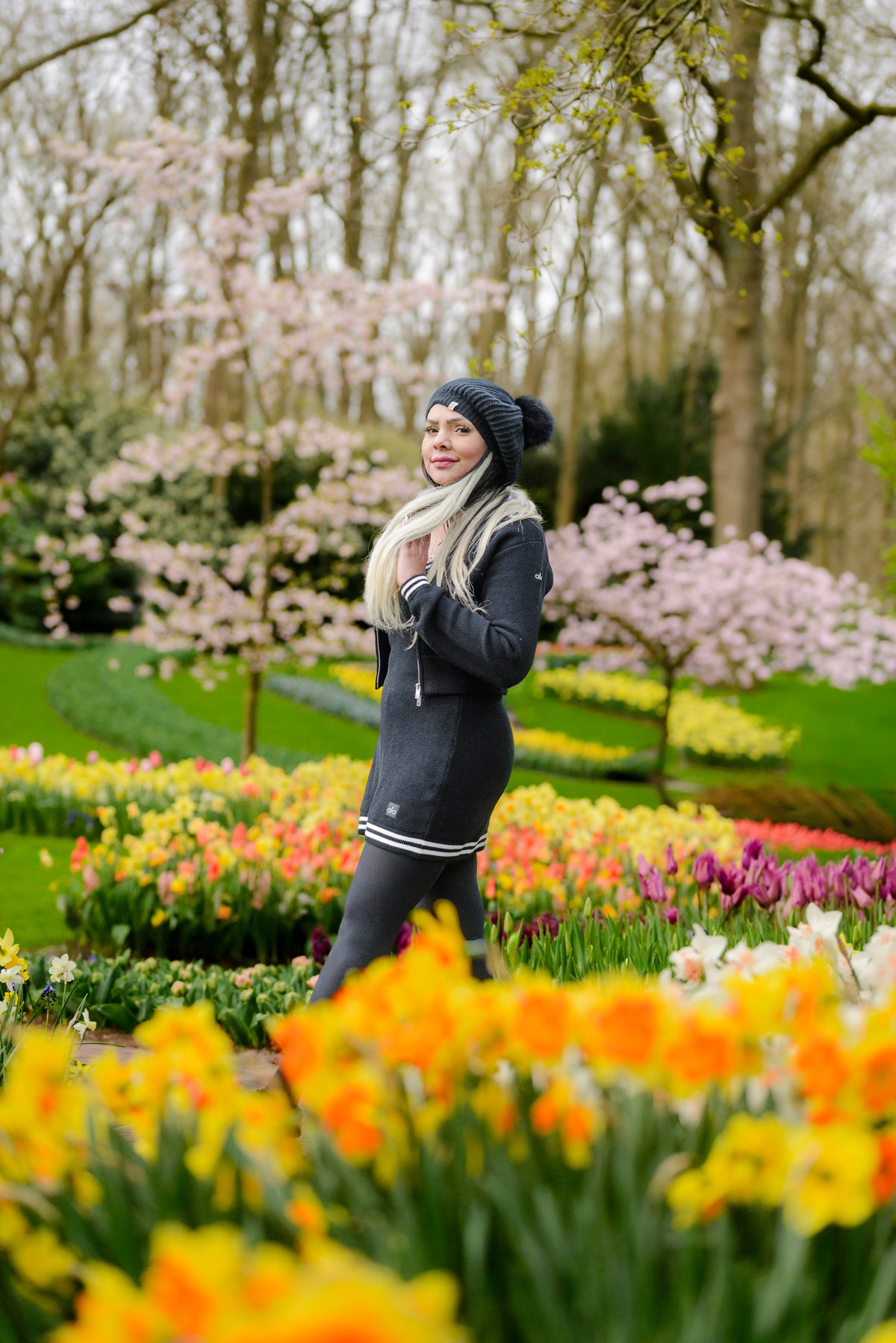 Female solo traveler walking at Keukenhof Garden. She is surrounded by flowers during her photo session in tulip season 2026. 