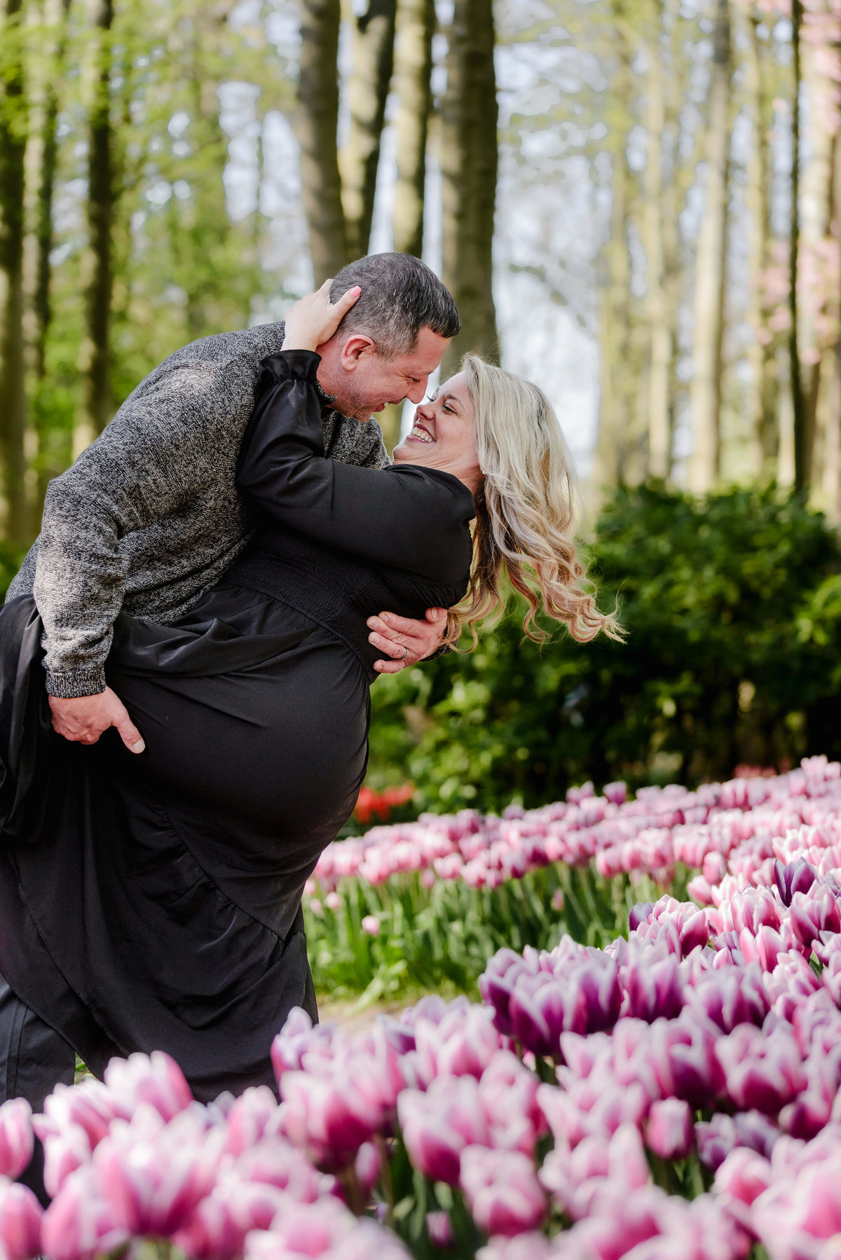 Couple embracing among red tulips during a spring photography session at Keukenhof Gardens