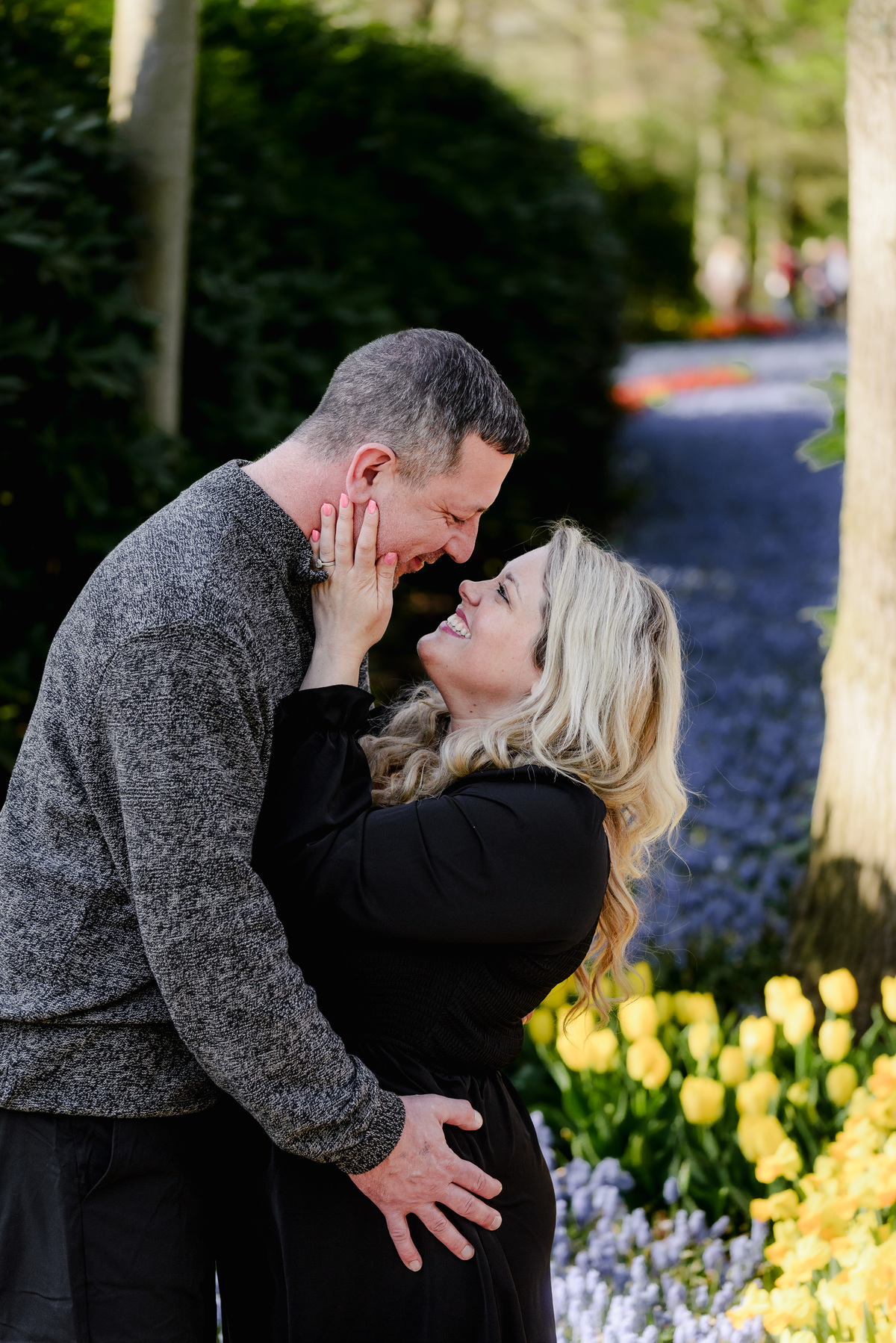 Couple portrait among blooming tulips during tulip season in the Netherlands