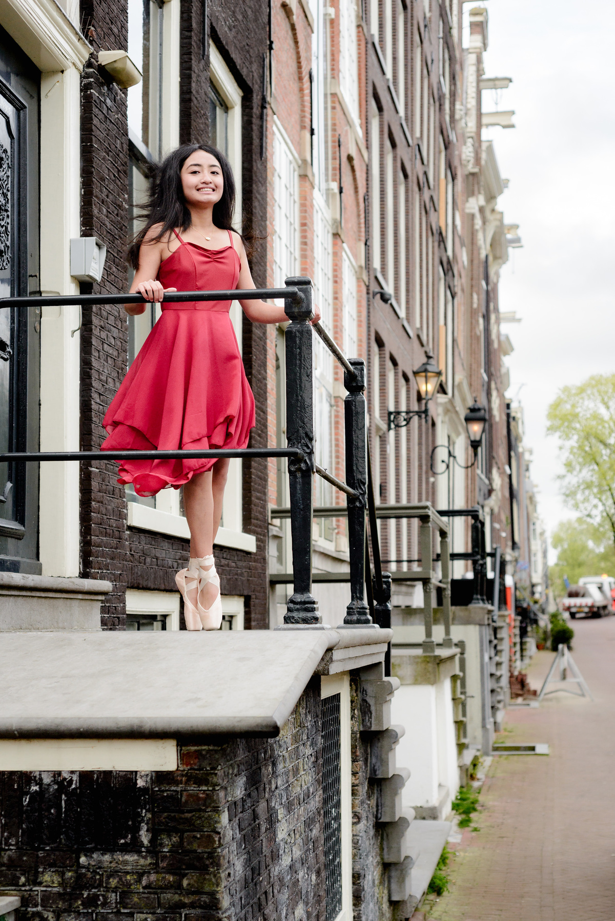 Ballet dancer posing beside historic canal houses in Amsterdam