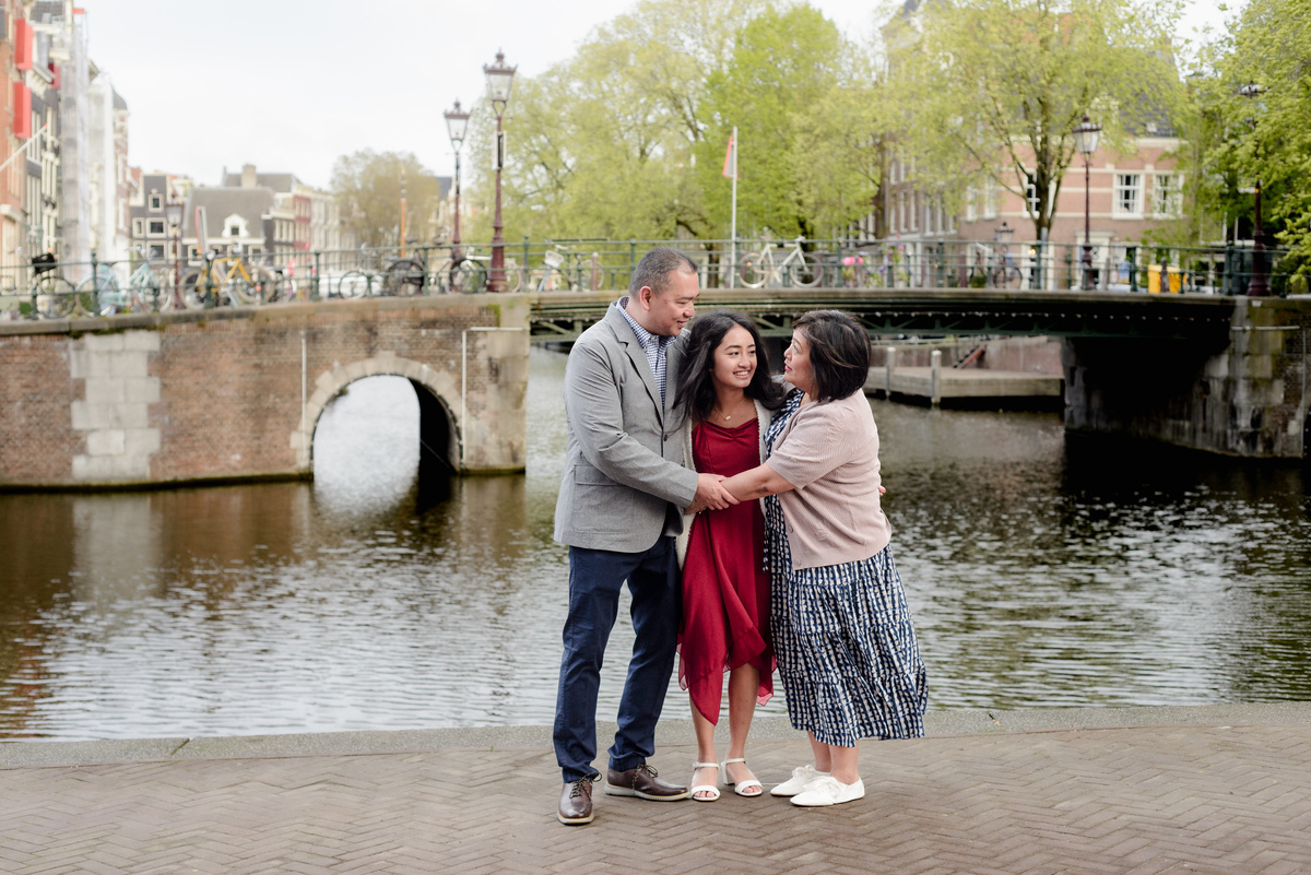 Family standing beside an Amsterdam canal during a photography session