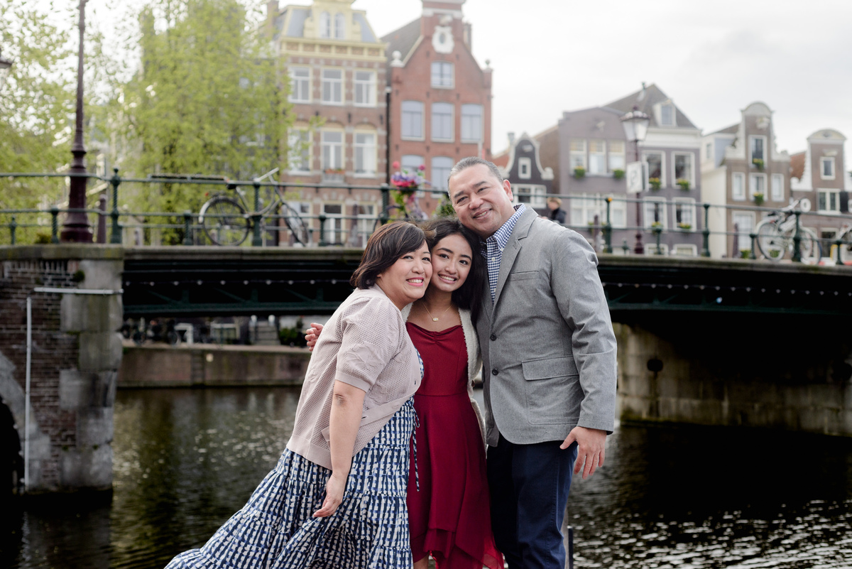 Family standing beside an Amsterdam canal during a photography session