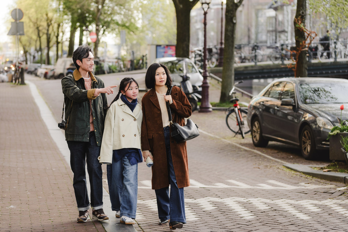 Family sitting beside a canal during a morning walk in Amsterdam