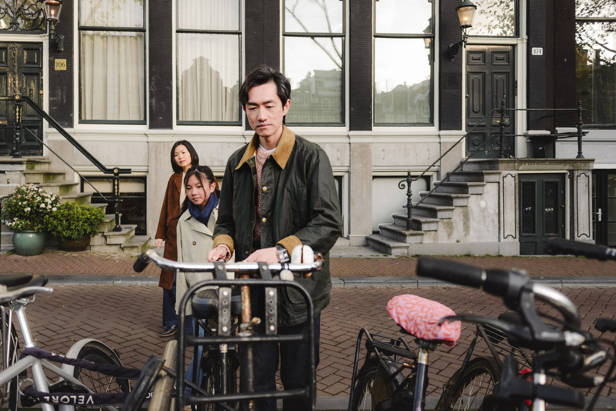 Father opening a bicycle lock while his wife and daughter look on in Amsterdam