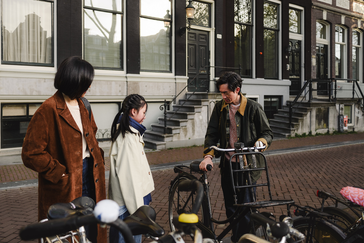 Father opening a bicycle lock while his wife and daughter look on in Amsterdam