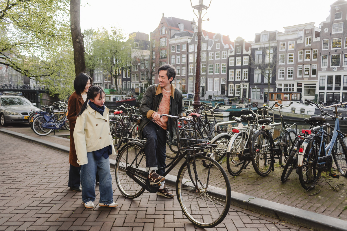 Family portrait beside a bicycle on a canal bridge in Amsterdam