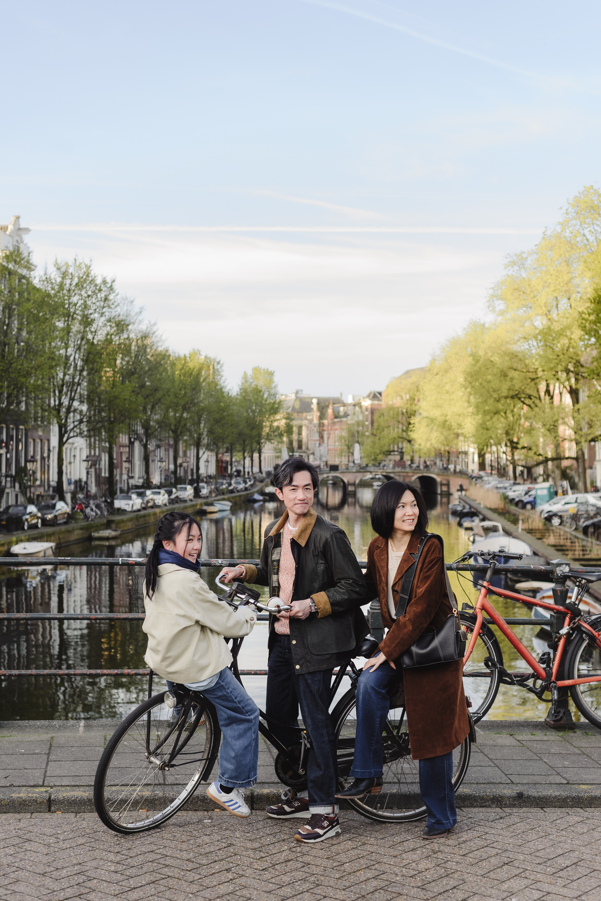Family portrait beside a bicycle on a canal bridge in Amsterdam