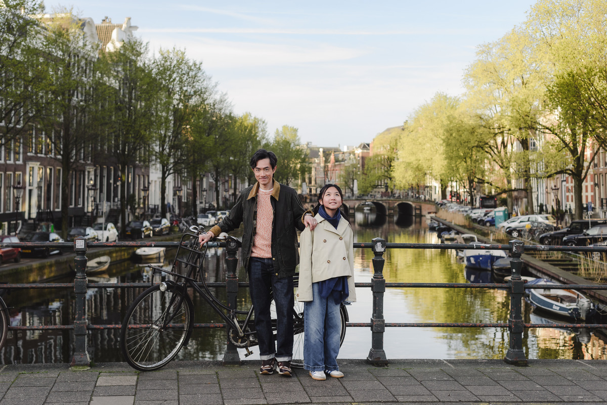 Father and daughter smiling next to a bicycle during a family visit to Amsterdam
