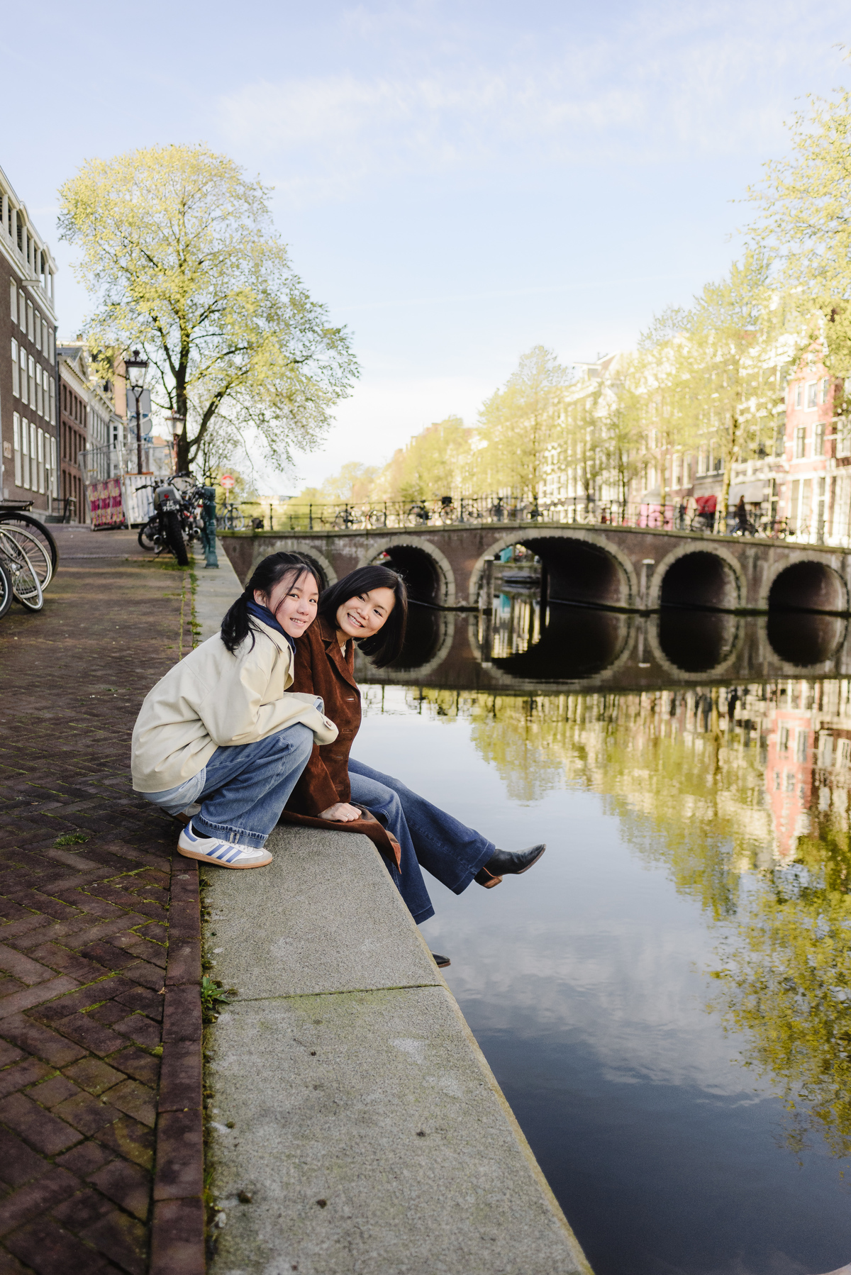 Mother and daughter relaxing beside a canal in Amsterdam