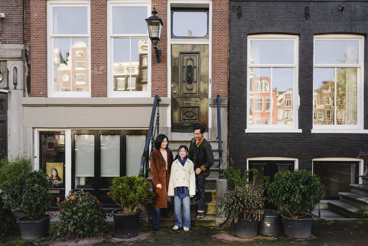 Family standing outside traditional canal houses in Amsterdam