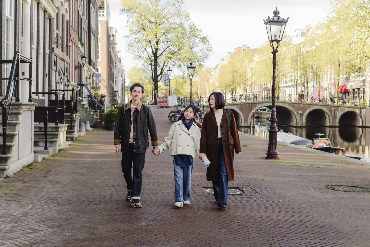 Family sitting beside a canal during a morning walk in Amsterdam