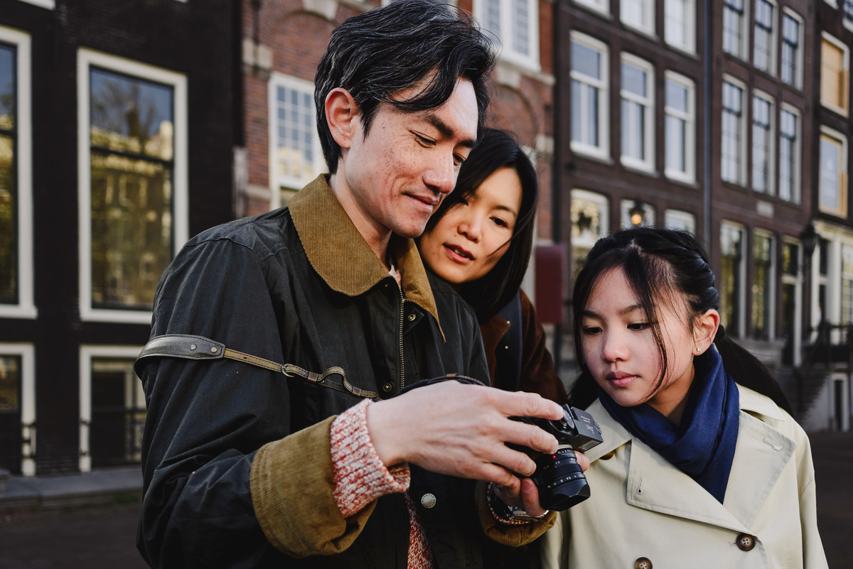 Father showing photos on his camera to his wife and daughter