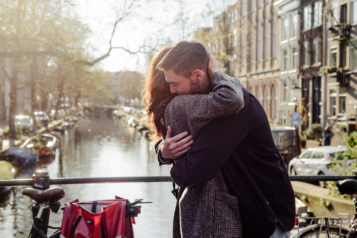 Couple embracing moments after a proposal on a bridge in Amsterdam