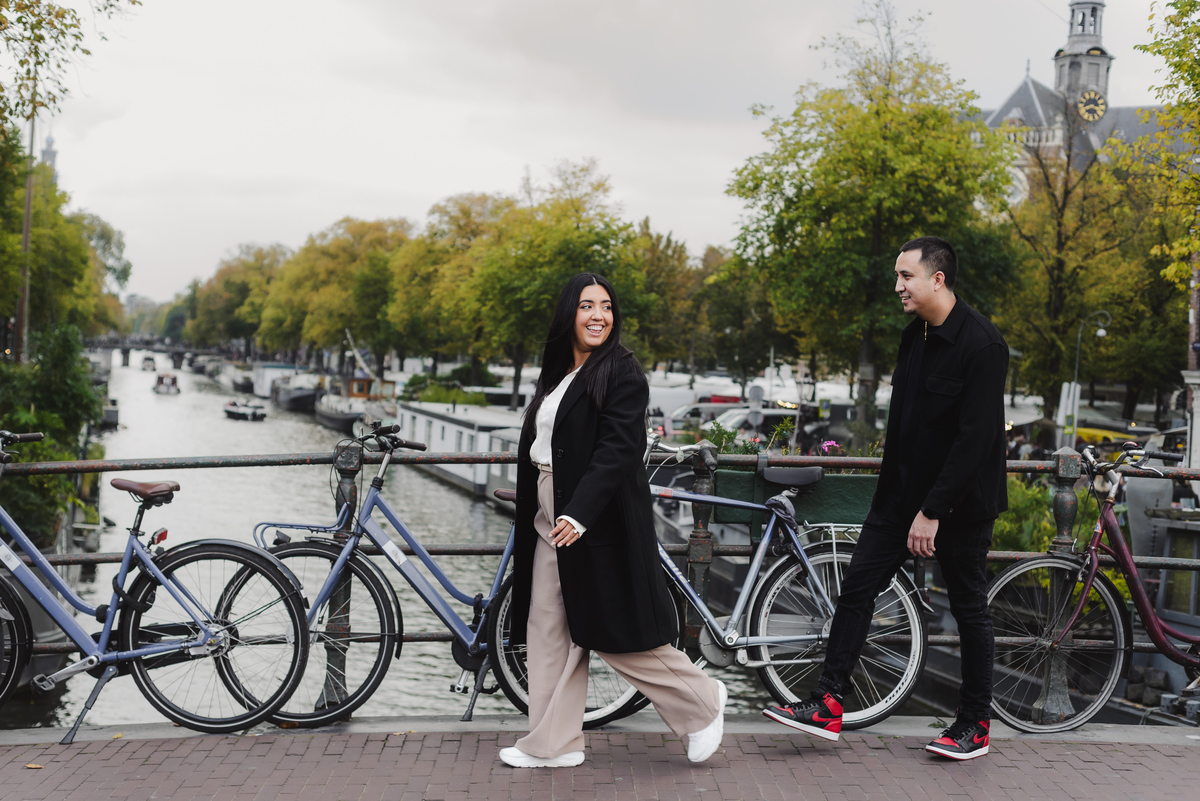 Recently engaged couple walking together along Prinsengracht during an engagement photography session in Amsterdam.