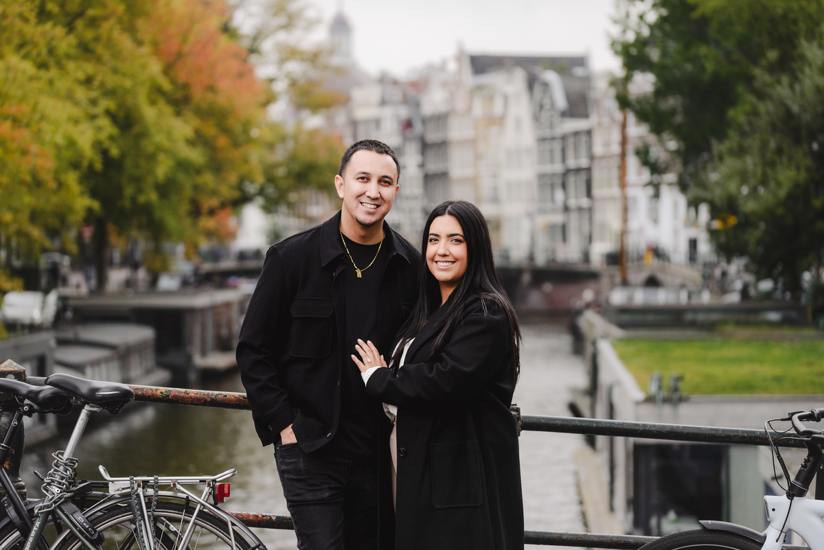 Engaged couple embracing on a bridge over Brouwersgracht during a post-proposal photography session in Amsterdam.
