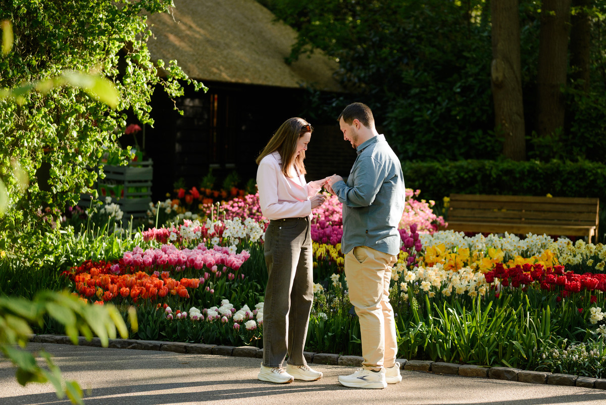 Man proposing on one knee among tulips at Keukenhof Gardens during a surprise engagement session.
