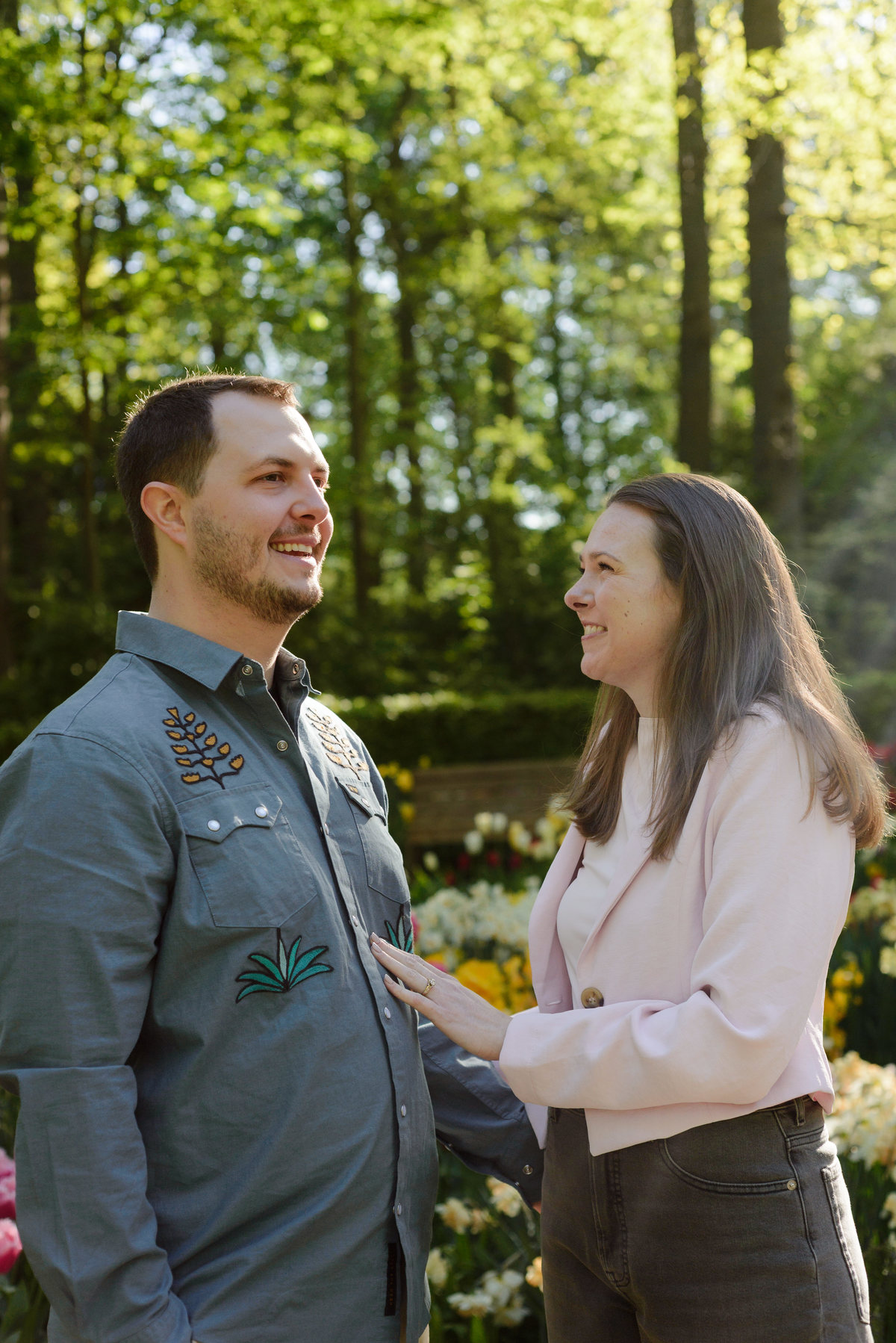 Newly engaged couple sharing a quiet moment among blooming tulips in the Netherlands.