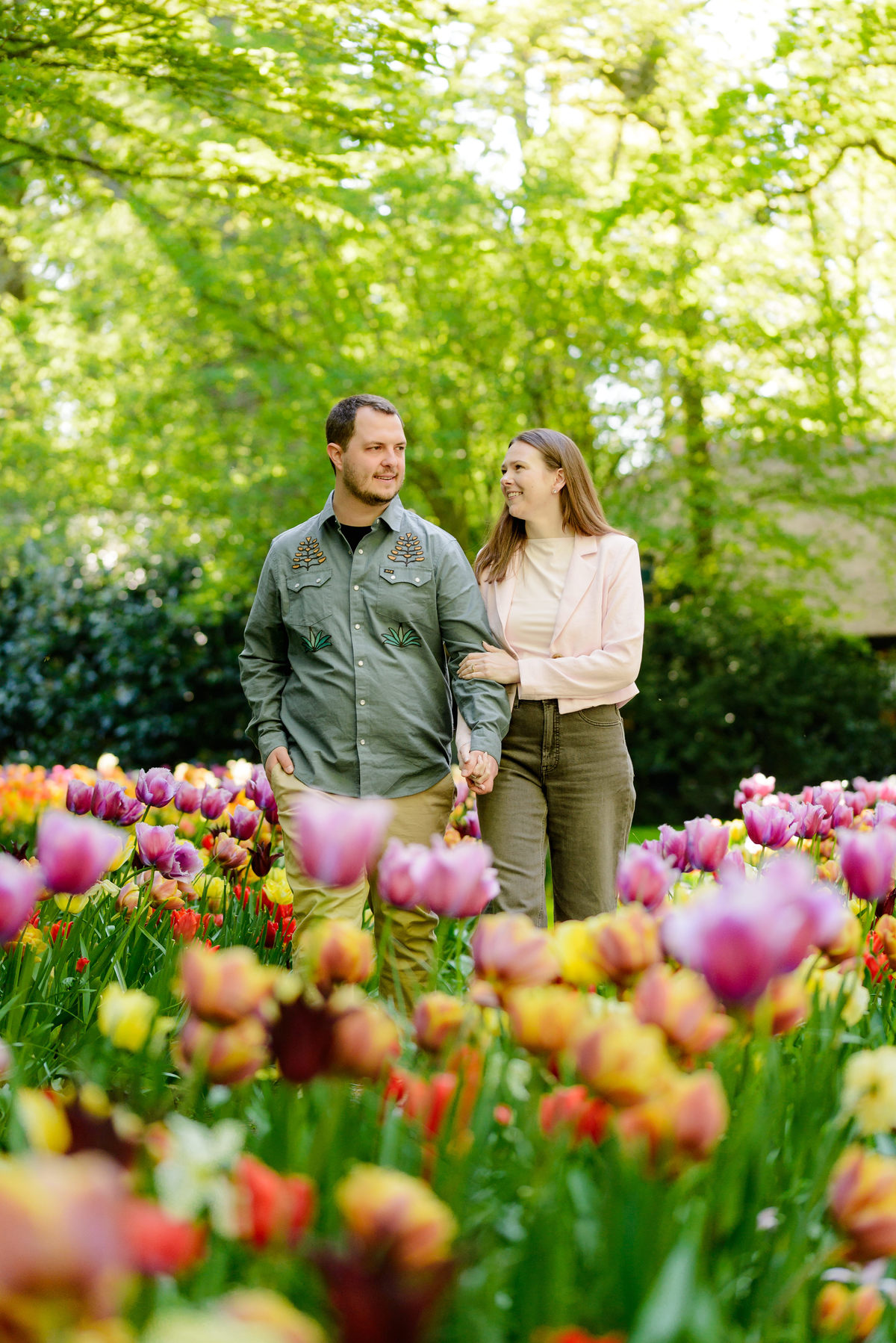 Couple photographed among blooming tulips during an engagement session in the Netherlands.