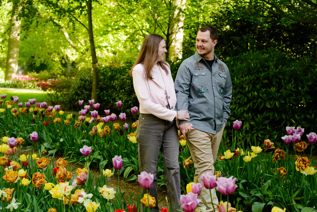 Couple relaxing among tulip displays after a surprise proposal.