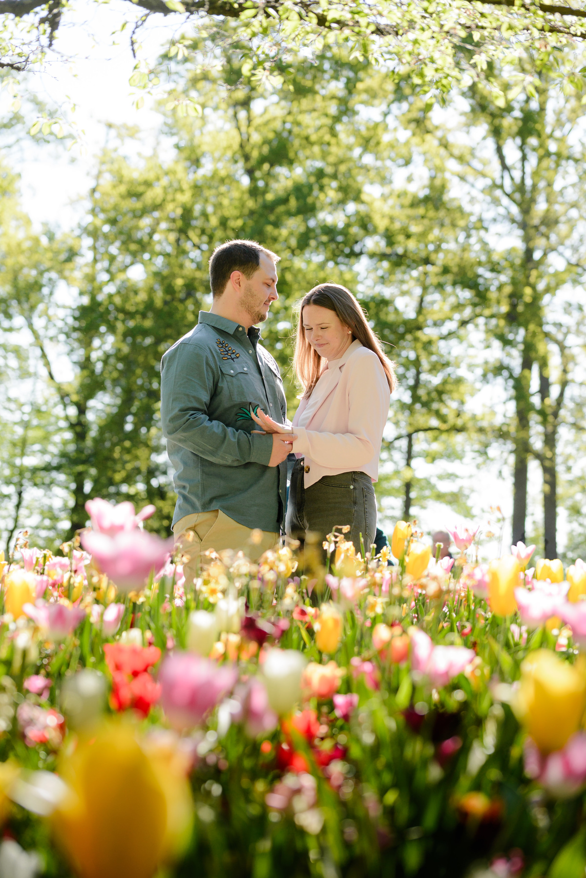 Couple embracing among colorful tulips during an engagement photography session.