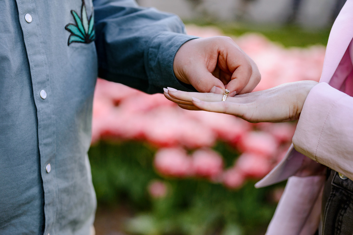 Close-up photograph of an engagement ring being placed on a hand after a surprise proposal.