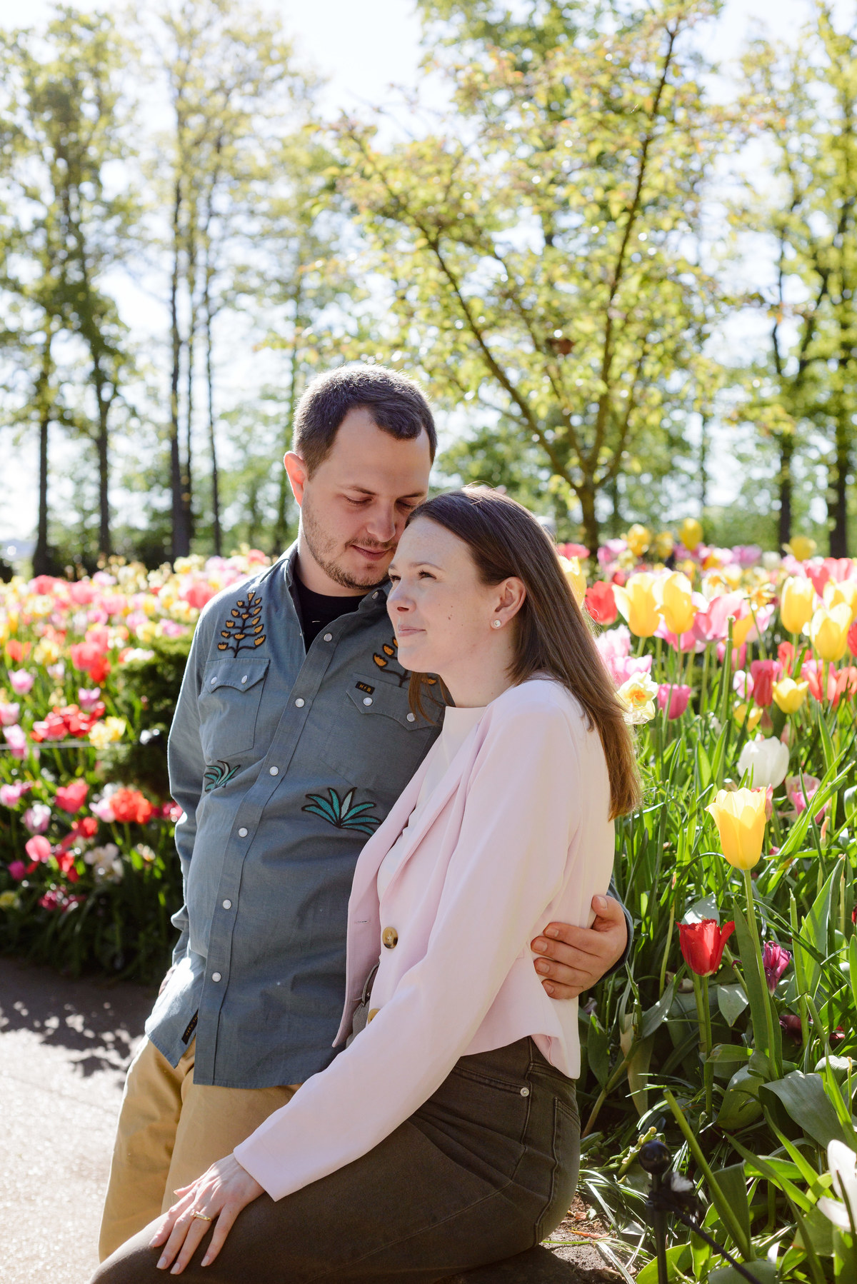 Newly engaged couple sharing a quiet moment among blooming tulips.