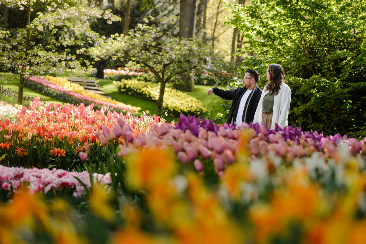 Couple standing together among colorful tulip beds at Keukenhof Gardens during spring.