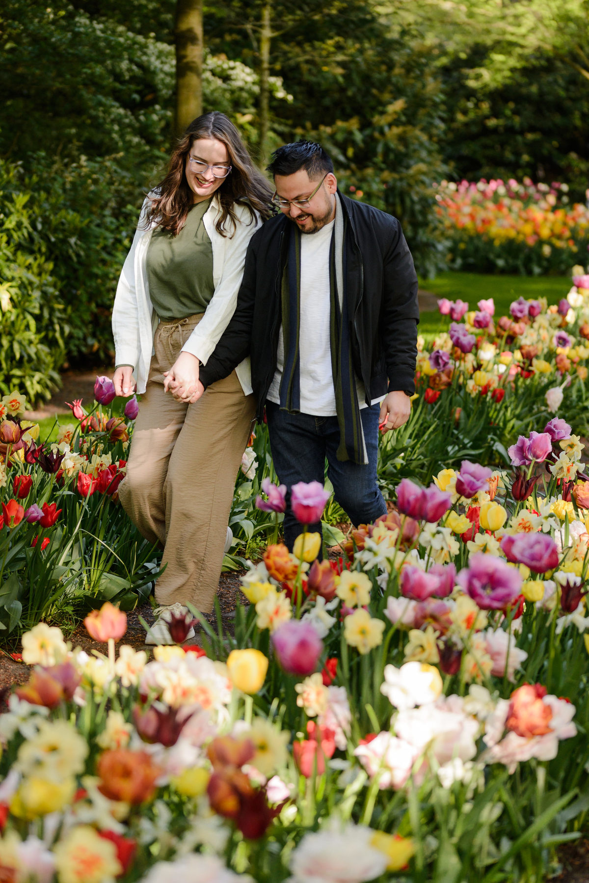 Couple walking hand in hand through blooming tulip gardens after a surprise proposal.