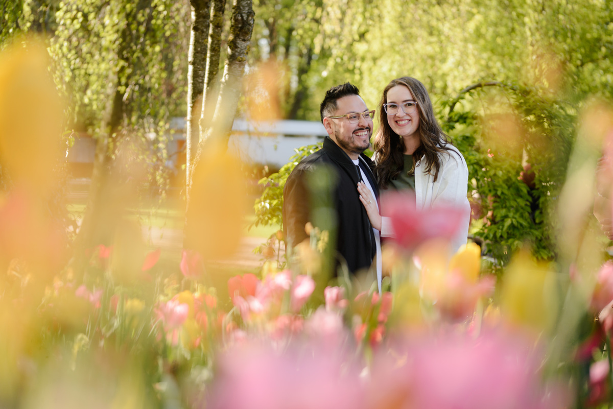 Engagement portrait framed by colorful tulips at Keukenhof Gardens during tulip season.