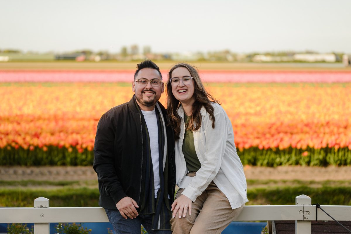 Newly engaged couple posing in front of Dutch tulip fields during spring in the Netherlands.