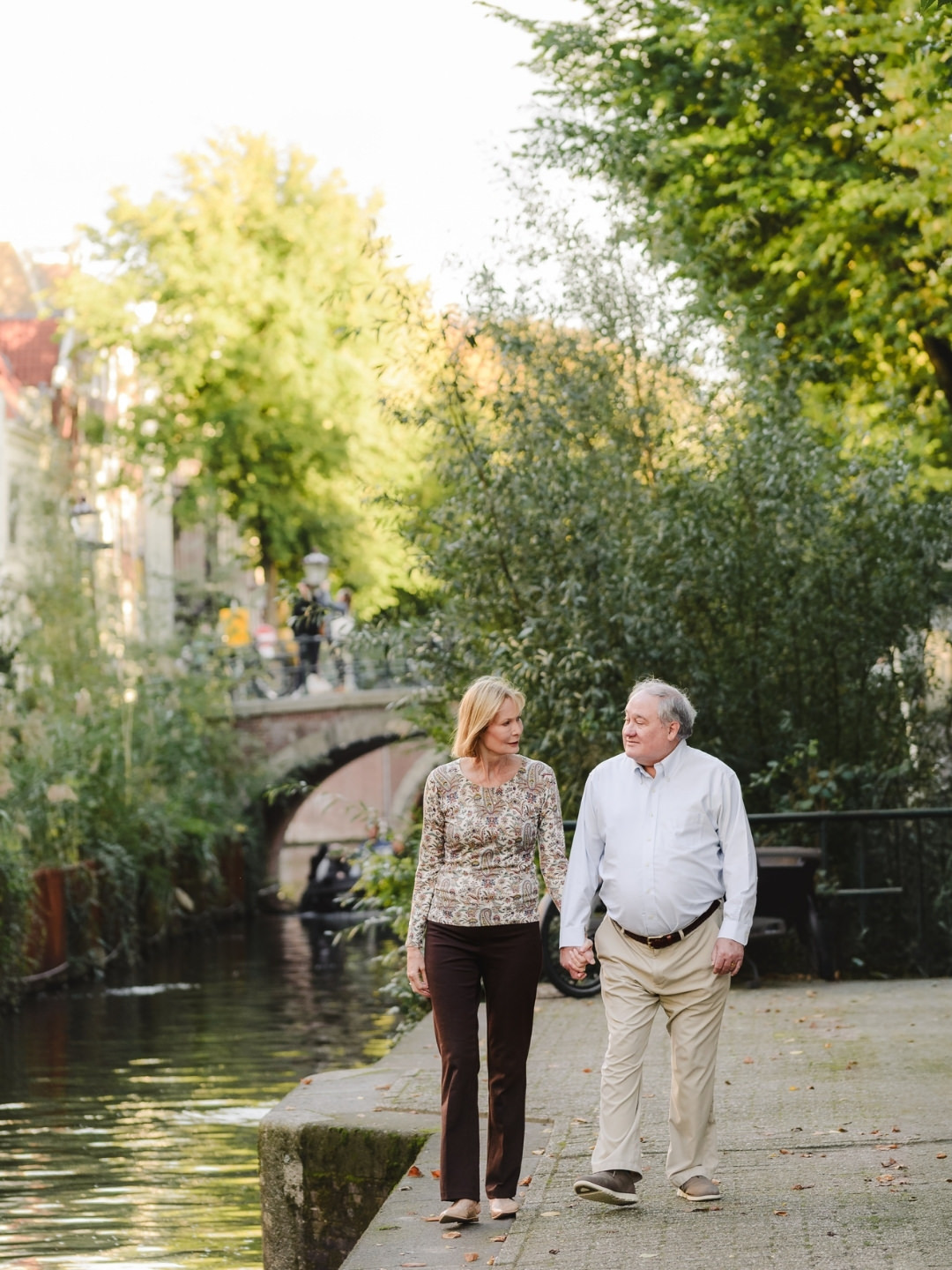 Couple walking together along a quiet canal path in Amsterdam during a lifestyle photography session.