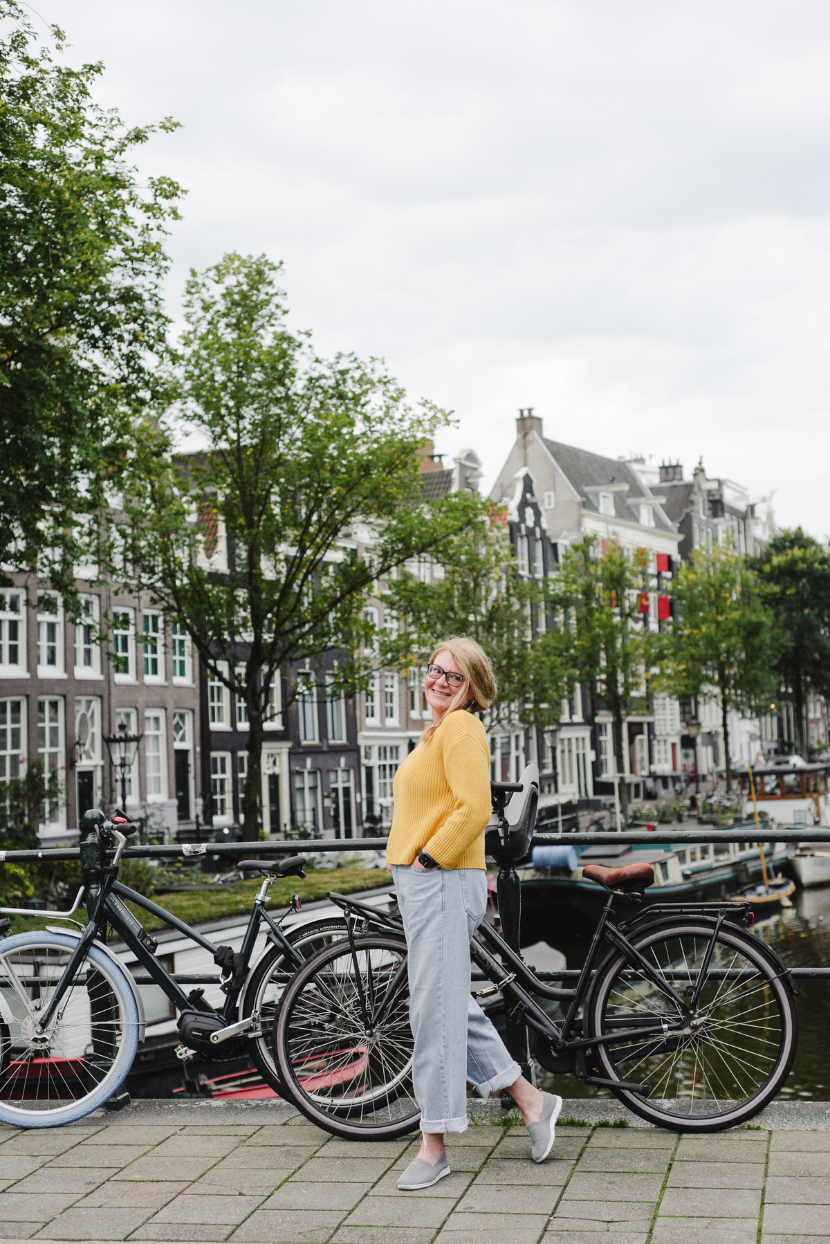 Female solo traveler wearing a yellow sweater, enjoying her trip in Amsterdam during her vacation for the session 