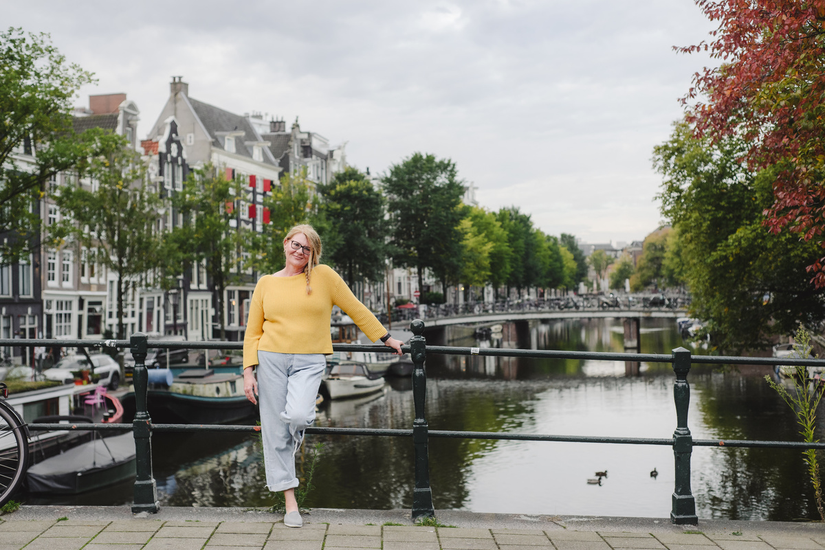 Female solo traveler posing during her morning vacation photo session in front of a canal in Amsterdam 