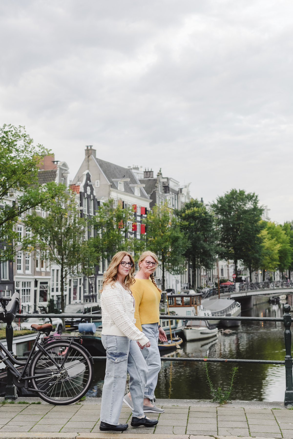 Sisters walking in front of a canal with a view of historical houses during a morning vacation photo session 
