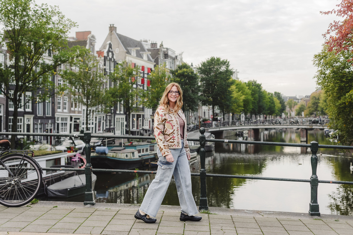 Travel agent capturing her trip in the streets of Amsterdam with a single canal and historical houses in the background 
