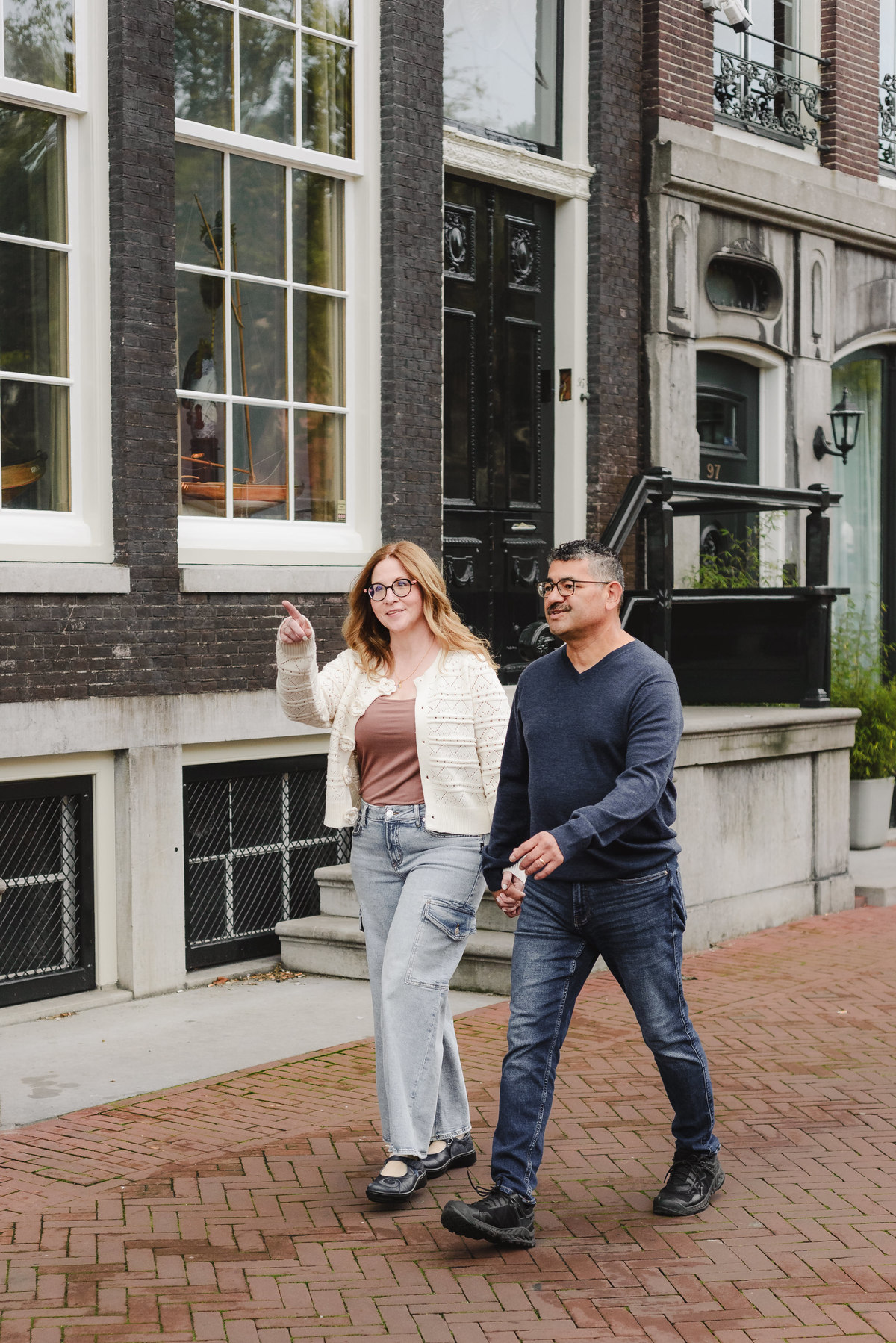 A couple walks hand in hand on the streets in Amsterdam. This is a vacation photography session. 