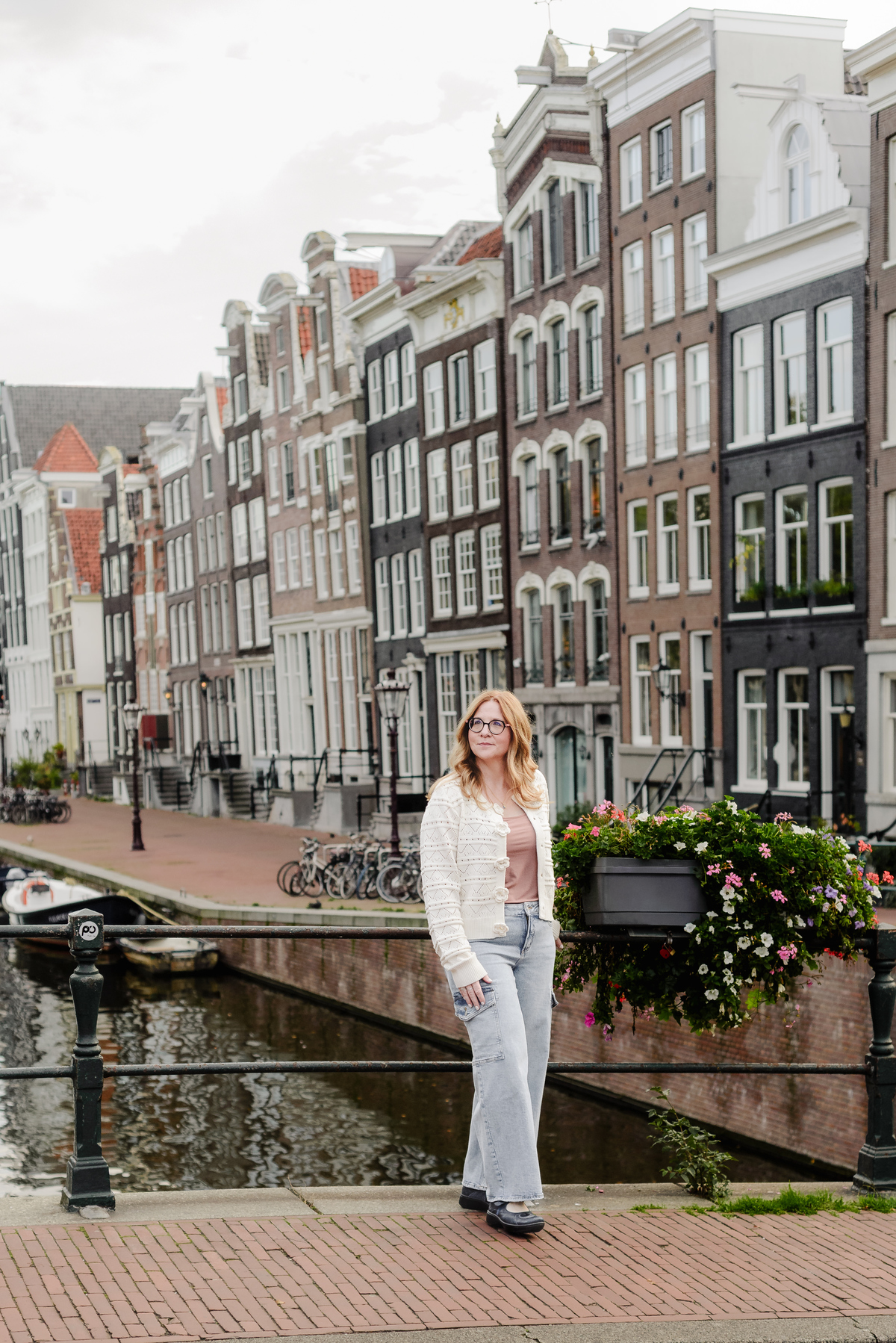 A female travel agent posing in front of historical houses in Amsterdam. This is the Herengracht in the early morning with empty streets during her vacation photography session. 
